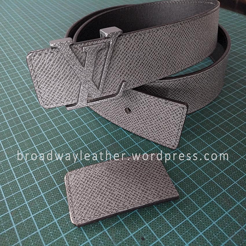 A shortened grey Louis Vuitton LV belt, with a segment of the cut off leather strap next to the belt